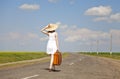 Lonely girl with suitcase at country road. Royalty Free Stock Photo