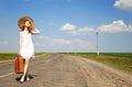 Lonely girl with suitcase at country road. Royalty Free Stock Photo