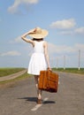 Lonely girl with suitcase at country road. Royalty Free Stock Photo