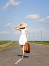 Lonely girl with suitcase at country road. Royalty Free Stock Photo