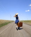 Lonely girl with suitcase at country road. Royalty Free Stock Photo