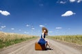 Lonely girl with suitcase at country road. Royalty Free Stock Photo