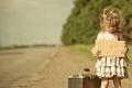 Lonely girl with suitcase standing about road