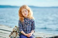 Lonely girl with a toy sitting on a pontoon near the water Royalty Free Stock Photo