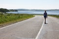 Lonely girl walking along the middle of the road on the background of the sea and the rural landscape. Royalty Free Stock Photo