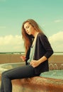 Lonely girl wants someone to talk. Wearing light gray sweater, black pants, an youg american woman sitting on red Royalty Free Stock Photo