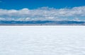 Lonely glittery white salt flat with a road and trucks on the horizon