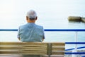 Lonely gray-haired elderly man sitting by the sea on a bench, a view from the back, contemplation of nature and a relaxing holiday Royalty Free Stock Photo