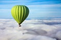 A lonely green hot air balloon floats above the clouds