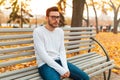 A lonely handsome man sits sad in the park on a bench. Autumn season