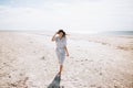 Lonely happy young woman in a hat and dress walks on a deserted sea beach on a sunny day. Summer vacation