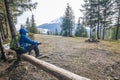 Lonely hiker traveler sitting on a log waching mountain scenery