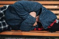 lonely homeless elderly old senior Caucasian man lying sleeping on park bench in autumn