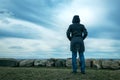 Lonely hooded female person from behind standing at seashore