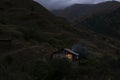 Lonely house in the mountains. Beautiful mountain landscape with a small house. Light in the window of the house. Smoke comes from Royalty Free Stock Photo