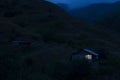 Lonely house in the mountains. Beautiful mountain landscape with a small house. Light in the window of the house. Smoke comes from Royalty Free Stock Photo