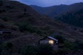 Lonely house in the mountains. Beautiful mountain landscape with a small house. Light in the window of the house. Smoke comes from Royalty Free Stock Photo