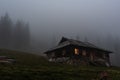 Lonely hut in the forest. Lonely wooden house in the mountains. Gloomy house with luminous windows. Royalty Free Stock Photo