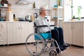 Lonely invalid man sitting in wheelchair looking through kitchen window Royalty Free Stock Photo