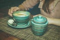 Lonely lady drinking coffee in the morning, side view of female hands holding stripped cup of hot beverage on wooden desk