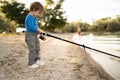 lonely little child fishing with fishing rod on lake, kid learning how to fish Royalty Free Stock Photo