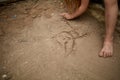 Lonely little girl drawing a cat with a pin in the sandy sidewalk, shallow depth of field Royalty Free Stock Photo