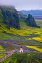 Lonely Lutheran Myrdal church surrounded by violet and pink lupine and yellow meadow flowers at Vik town, South Iceland, at summer