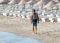 A lonely male traveler walks along the seashore with a backpack on his back. Local Beach on the island of Cyprus