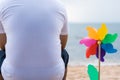 Lonely man on the beach above a boat looking at the sea. The young man wears a white shirt with a colorful pinwheel Royalty Free Stock Photo