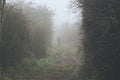 Lonely man disappearing in a fog during a cold dark day