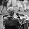 Lonely man is having breakfast. Senior man in street cafe