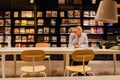 Lonely man reading new magazines inside library or modern bookstore with press and books