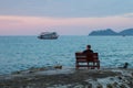 Lonely man sits on a bench on the coast looking at the sea. Travel. Royalty Free Stock Photo