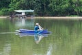 Lonely man sits in the boat and collects the fish from the net with forest in background