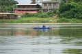 Lonely man sits in the boat and collects the fish from the net with forest in background