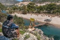 Lonely man sits looking at the wooden bridge in the mountains