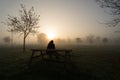 Lonely man silhouette sitting on a bench on a foggy morning Royalty Free Stock Photo