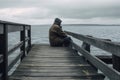 A lonely man sitting on the dock of a bay looking out to the water created by generative AI Royalty Free Stock Photo