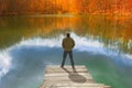 Lonely man standing on the edge of the small wooden pier looking at the lake Royalty Free Stock Photo