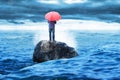 Lonely man standing on rock with red umbrella Royalty Free Stock Photo