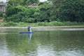 Lonely man stands on the boat and collects the fish from the net with forest in background