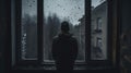 A lonely man stands in front of a window