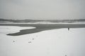 A lonely man stands on a snow-covered river bank on a snowy winter day Royalty Free Stock Photo