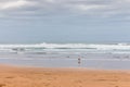 Lonely man walk on seashore on cloudy day. Huge wave on the beach with tourist. Panoramic seascape. Autumn on the coast, Spain. Royalty Free Stock Photo