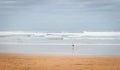 Lonely man walk on seashore on cloudy day. Huge wave on the beach with tourist. Panoramic seascape. Autumn on the coast, Spain.