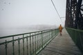 Lonely man walking on bridge against city in mysterious fog