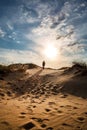 Lonely man walking in the desert dunes at sunset Royalty Free Stock Photo