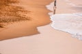 Lonely man walking on golden sand beach with ocean waves, low tide at sunset, beautiful background, colorful landscape Royalty Free Stock Photo