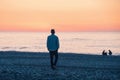 Lonely man walking on the sea coast at sunset. Male with mental problems on the beach by the ocean. Loneliness Royalty Free Stock Photo