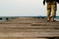 A lonely man walking in wooden harbour